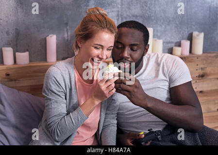 Gamer paar Essen Muffins im Schlafzimmer Stockfoto