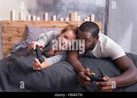 Freudige paar Spielen von Videospielen im Bett Stockfoto