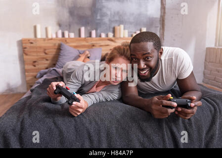Überglücklich Paar genießt Videospiele im Bett Stockfoto