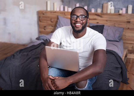 Fröhliche Mann mit Laptop im Schlafzimmer Stockfoto