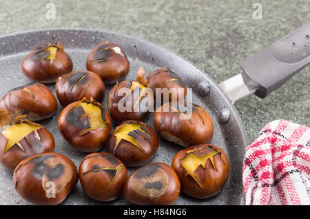 Gebratene Kastanien auf einem Stein Kochen Pfanne Stockfoto