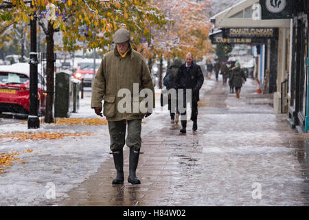 Ilkley, West Yorkshire, Großbritannien. 9. November 2016. Es schneit und ein Mann (zusammen mit anderen Fußgänger tragen Stiefel, Handschuhe, Mützen und Wintermäntel) ist Fuß vorbei an Geschäften auf The Grove - Ilkleys ersten Schneefall 2016. Bildnachweis: Ian Lamond/Alamy Live-Nachrichten Stockfoto