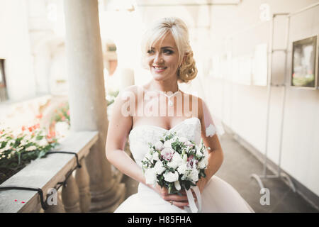Wunderschöne Braut mit einem luxuriösen weißen Kleid posiert in der Altstadt Stockfoto