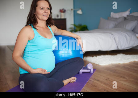 Schwangere Mutter sitzt auf Gymnastikmatte Stockfoto