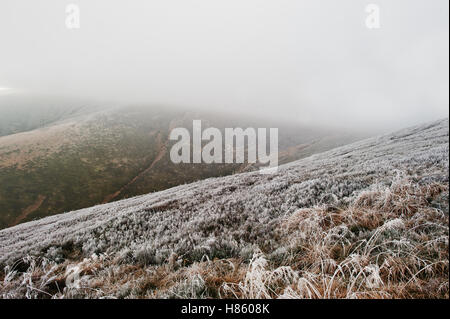 Berghänge mit gefrorenen Rasen und Nebel auf Hügel. Stockfoto