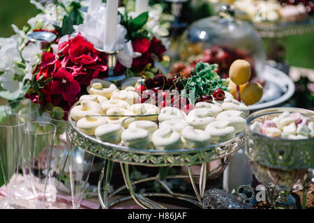 schöne Süßigkeiten und Blumen auf dem Tisch Stockfoto