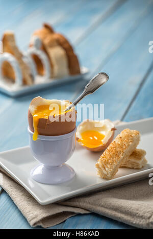 Weich gekochtes Ei zum Frühstück mit Toast im Hintergrund Stockfoto