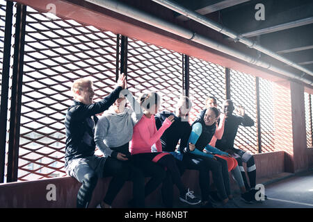 Seitenansicht der Jugendlichen in der Sportswear vor hellen Fenster sitzen und Spaß haben. Exemplar Stockfoto