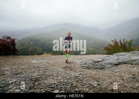 junges Mädchen Läufer laufen im Regen mit einem Lächeln im Gesicht während Crimea Bergmarathon Stockfoto