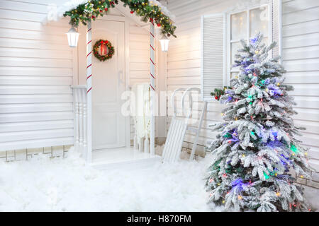 Winter-Exterieur eines Landhauses mit Weihnachtsdekoration im amerikanischen Stil. Verschneiten Innenhof mit einer Veranda Baum ein Stockfoto