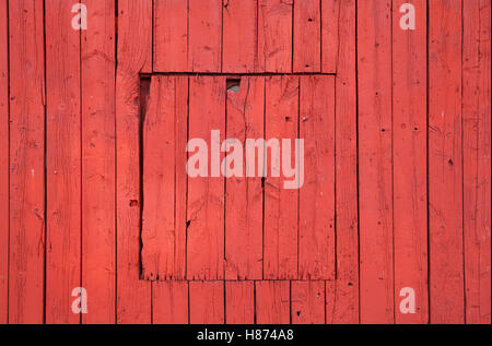 Alte rote Holzwand mit geschlossenen quadratischen Fenster, flache Hintergrundtextur Foto Stockfoto