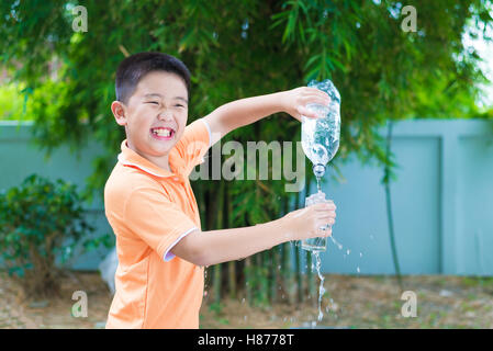 Asiatische junge gießt Wasser in Glas aus Flasche, im Garten, grüner Hintergrund Stockfoto