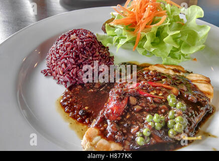 Fisch gebraten und schwarzer Pfeffer-Sauce serviert mit Reis von gesunden und Salat auf die weiße Schale, weich konzentriert Stockfoto