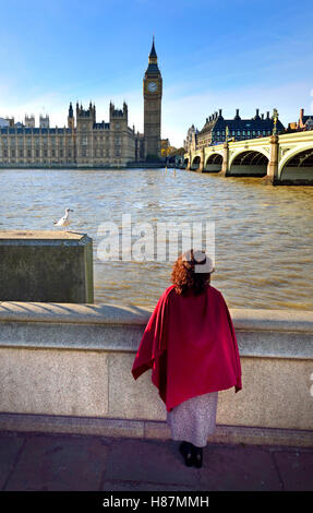 London, England, Vereinigtes Königreich. Frau auf der South Bank, Blick über die Themse, die Houses of Parliament - mit einer Möwe Stockfoto