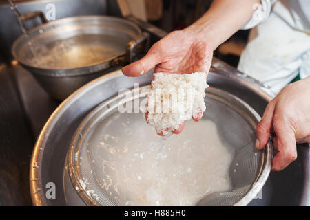 Ein Koch arbeitet in einer kleinen Großküche, Itamae oder Meisterkoch Sushi machen. Zubereitung von Reis für die Gerichte. Stockfoto