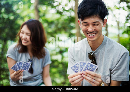 Junge Frau und Mann sitzt in einem Wald, Spielkarten. Stockfoto