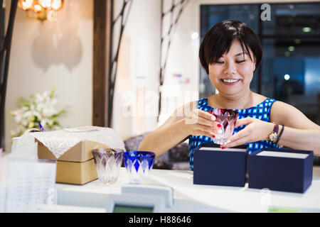 Verkäuferin in einem Laden verkaufen Edo Kiriko schneiden Glas in Tokio, Japan. Stockfoto