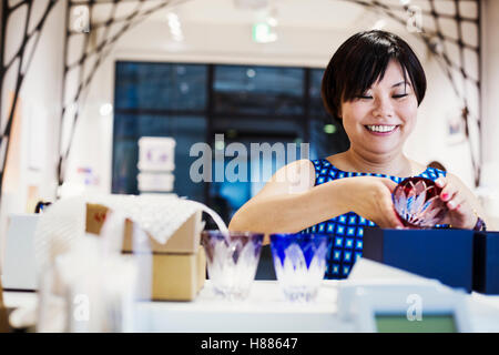 Verkäuferin in einem Laden verkaufen Edo Kiriko schneiden Glas in Tokio, Japan. Stockfoto