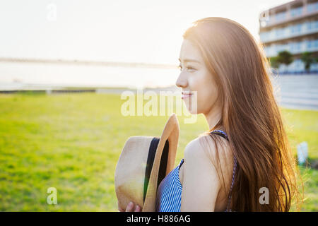 Lächelnde junge Frau mit langen braunen Haaren, mit Panamahut. Stockfoto