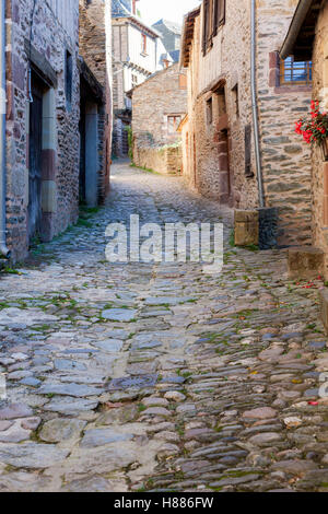 Eine gepflasterte Gasse in Conques (Frankreich). Das mittelalterliche Dorf zeigt Touristen seine Abteikirche und Häuser mit Schieferdächern gekrönt Stockfoto