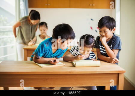 Eine Gruppe von Kindern in einem Klassenzimmer mit ihrer Lehrerin. Stockfoto