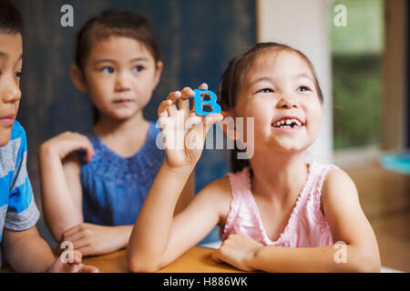 Eine Gruppe von Kindern in der Schule. Zwei jungen und zwei Mädchen Alphabet Buchstaben hochhalten. Stockfoto