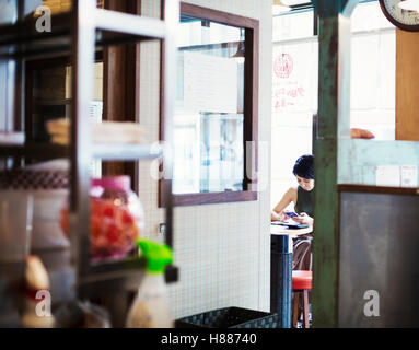 Die Ramen-Nudel-Shop. Eine Frau sitzt in einem Café, Blick durch eine Tür. Stockfoto