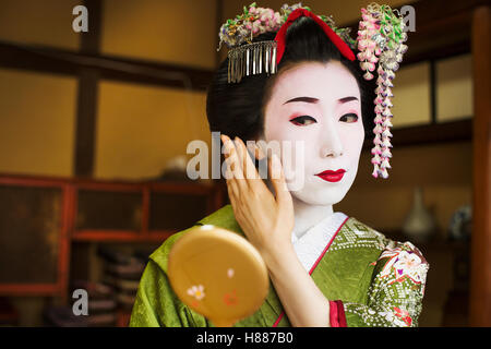 Eine Frau hat sich im Stil traditionellen Geisha, Blick in einen Handspiegel. Stockfoto