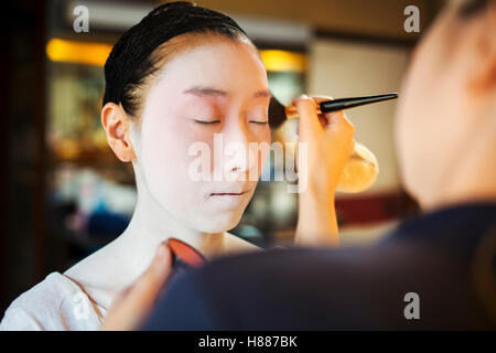 Eine moderne Geisha und Maiko-Frau in traditioneller Weise mit weißem Gesicht Make-up vorbereitet. Stockfoto