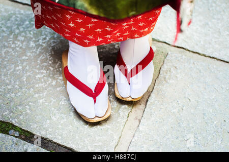 Eine traditionelle Geisha Frau die Füße, in hölzernen Sohlen Sandalen mit roten Riemen und weiße Strümpfe oder Tabi. Stockfoto
