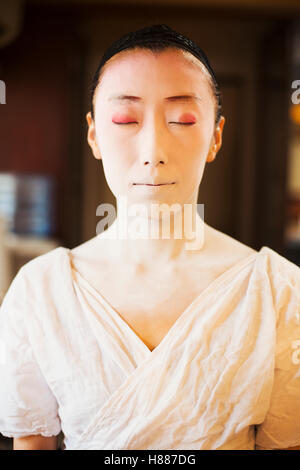 Eine moderne Geisha und Maiko-Frau in traditioneller Weise mit weißem Gesicht Make-up vorbereitet. Stockfoto