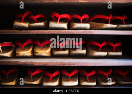 Reihen von traditionellen Holz-Sandalen mit dicken Sohlen und roten Bändern von Geisha, Okobo oder Geta getragen. Stockfoto