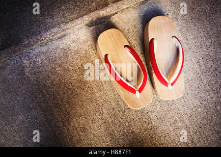 Ein paar traditionelle hölzerne Sandalen mit dicken Sohlen und roten Bändern von Geisha, Okobo oder Geta getragen. Stockfoto