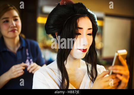 Eine Geisha oder Maiko mit Friseur- und Make-up-Künstler erstellen die traditionelle Frisur und Make up. Stockfoto