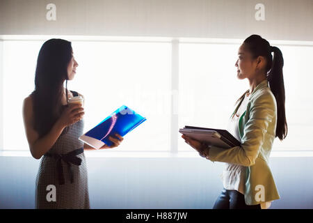 Zwei Unternehmerinnen im Gespräch vor einem Fenster im Büro. Stockfoto