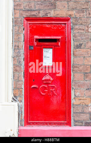 Leuchtend rote Royal Mail-Briefkasten in Ziegelwand montiert Stockfoto