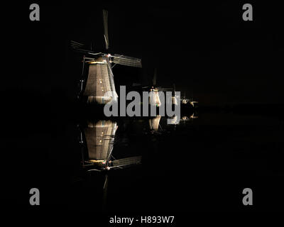 Fünf leuchtende Windmühlen, mit Spiegelbild im Wasser des Kanals in die dunkle schwarze Nacht in Kinderdijk, Niederlande. Stockfoto