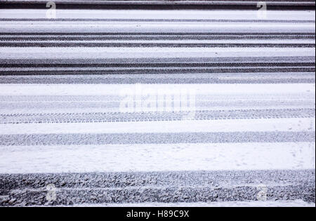 Hintergrundtextur Asphaltstraße bedeckt mit Schnee und Reifen Spuren Stockfoto