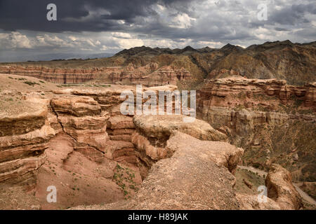 Touristen auf Klippe am Tscharyn Canyon Park mit Wolken und Tien Shen Berge Kasachstan Stockfoto