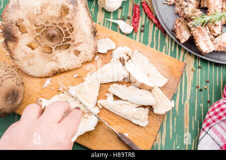 Frau Hand schneiden Sonnenschirm Pilze auf einem Brett Stockfoto