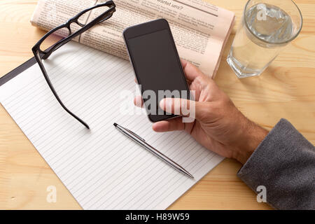 Zeitungen und Kaffeetasse, Lesebrille, gestreiften Papier, Hände halten, Handy, Handy, Taschenrechner. Stockfoto