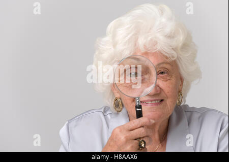 Ältere Frau, die gerade durch eine Lupe Stockfoto