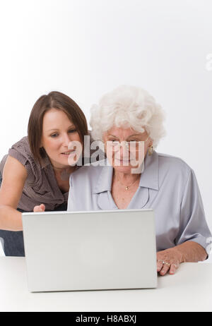 Junge Frau, die helfen, ältere Frau mit einem laptop Stockfoto