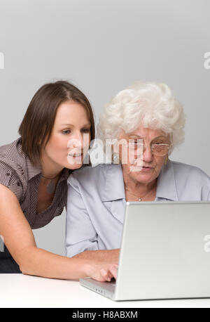 Junge Frau, die helfen, ältere Frau mit einem laptopp Stockfoto