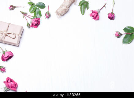 Die Zusammensetzung, Muster aus roten Rosen, ein Geschenk auf einem weißen Hintergrund. Rahmen der Blumen. Soft-Fokus. Ansicht von oben. Stockfoto