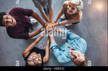 Draufsicht auf junge Menschen stehen zusammen blickte Kamera mit stilvollen jungen Mann gestikulierte Victory-Zeichen. Stockfoto