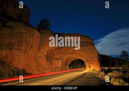Ein Auto Lichter Streifen durch einen kleinen Tunnel in einem roten Felsen zu Tage tretenden auf Scenic Byway 12 in Red Canyon in der Nähe von Panguitch Utah USA Stockfoto
