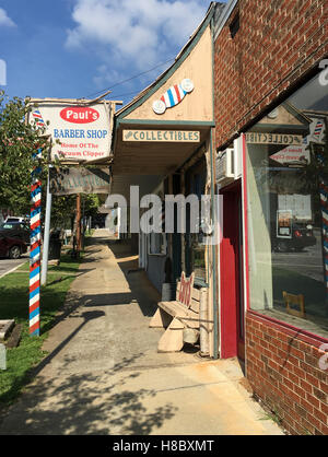 Ein Blick auf einem Bürgersteig in einer Kleinstadt, Clayton, Ga, Frisörsalon und eine freie Ladenfront zeigen. Stockfoto