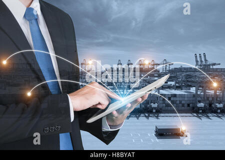 Doppelbelichtung Geschäftsmann Hand hält digitale Tablet Unterstützung Kontrolle Logistik Systemnutzung für Export und Logistik Stockfoto