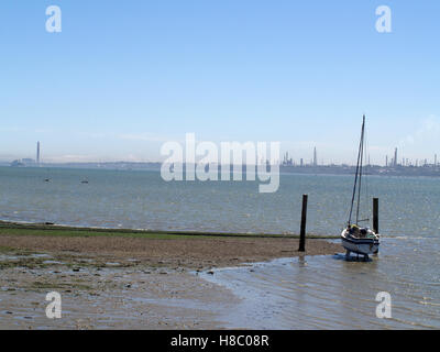 Mann, der auf die Erhaltung der Yacht zu Weston Shore, Woolston, Southampton, Hampshire, UK mit Fawley Raffinerie in Ferne arbeitet Stockfoto